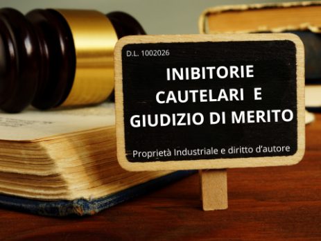 Martelletto del giudice e libri di diritto con lavagnetta che riporta D.L. 100/2026 — inibitorie cautelari e giudizio di merito in proprietà industriale e diritto d'autore