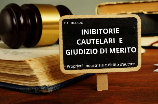 Martelletto del giudice e libri di diritto con lavagnetta che riporta D.L. 100/2026 — inibitorie cautelari e giudizio di merito in proprietà industriale e diritto d'autore