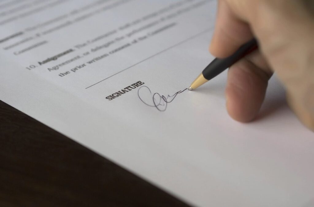 Condizioni generali di vendita e di acquisto Firma di un contratto commerciale con penna su documento cartaceo